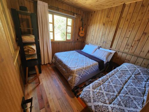1 dormitorio con 2 camas en una cabaña de madera en Colina Branca, en Rio Rufino