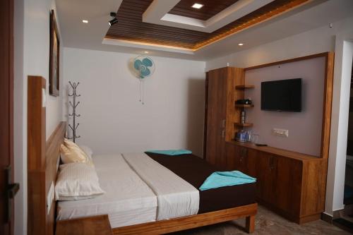 a bedroom with a bed and a flat screen tv at Bhuvanam homestay in Kalpetta