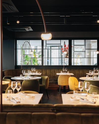 a restaurant with tables and chairs and windows at The CORNR Hotel in Nieuwpoort