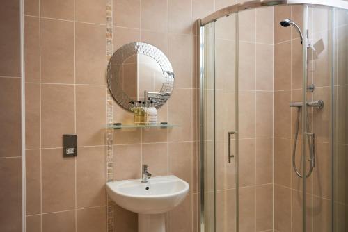 a bathroom with a sink and a shower with a mirror at Victoria Mills Apartment Shipley in Shipley