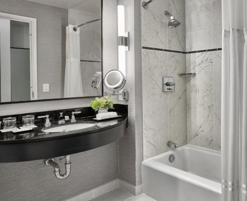 a bathroom with a sink and a tub and a mirror at Loews Philadelphia Hotel in Philadelphia