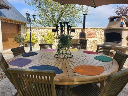 un tavolo in legno con sedie imbottite colorate e un ombrellone di chez Carline charmante petite maison gîte de France 3 epis a Fultot
