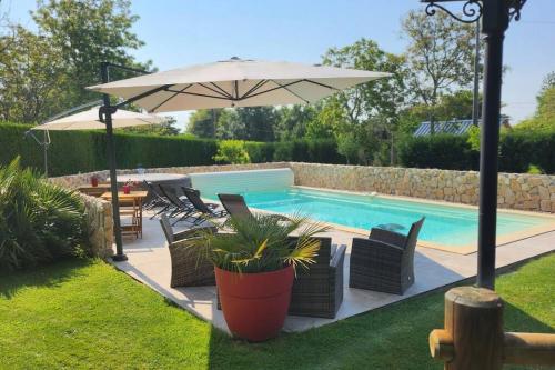 una piscina con sedie e ombrellone in un cortile di chez Carline charmante petite maison gîte de France 3 epis a Fultot