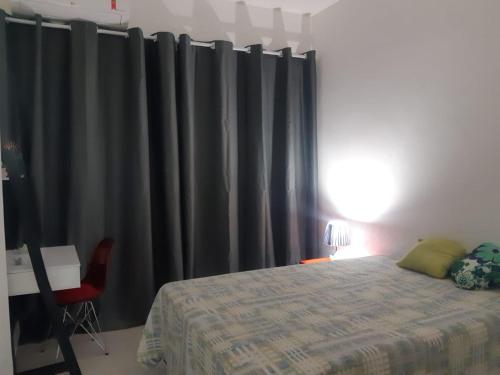 1 dormitorio con cortinas negras, 1 cama y 1 silla en Lev Apartments - Apto Beira-Mar - Posto 2 - Copacabana, en Río de Janeiro