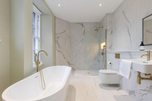 a white bathroom with a tub and a sink at Dragon Suites Luxury Serviced Apartments at Walker Street in Edinburgh