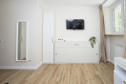 a white living room with a dresser and a tv at Sant'Erasmo Rooms in Rome