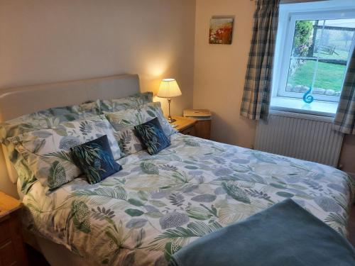 a bedroom with a bed and a window at Laghead Steading Cottage in Gatehouse of Fleet