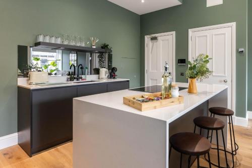 a kitchen with green walls and a white island with stools at Dragon Suites Luxury Serviced Apartments at Walker Street in Edinburgh