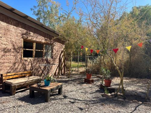 a garden with a bench and a table and flags at CaminAndes Hostal in San Pedro de Atacama