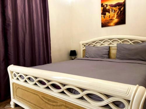 een slaapkamer met een groot wit bed en paarse gordijnen bij Cosy appartement au super centre ville avec vue partielle sur le parc in Agadir
