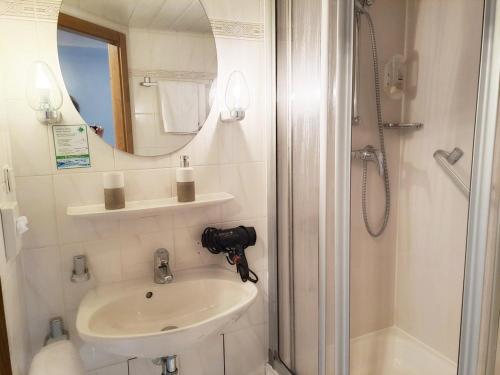 a bathroom with a sink and a shower with a mirror at Stadthotel Waldhorn in Kirchheim unter Teck