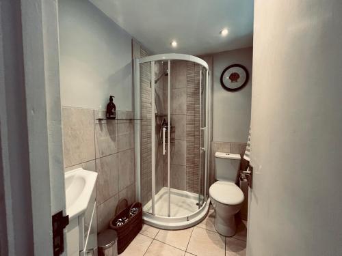 La salle de bains est pourvue d'une douche, de toilettes et d'un lavabo. dans l'établissement Pass the Keys Scallop Cottage Oasis of Calm, à Rye