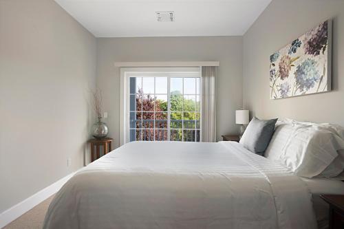 a white bedroom with a large bed and a window at The Cliffside Resort Condominiums in Greenport