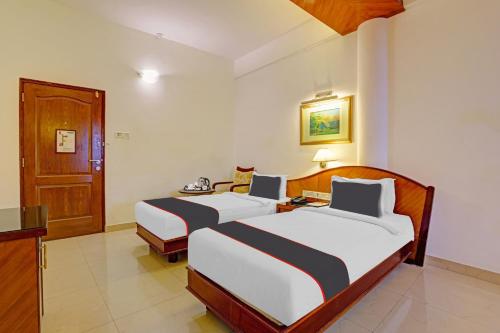 a hotel room with two beds and a door at Hotel Indraprastha in Trivandrum