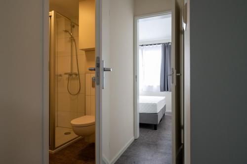 a bathroom with a toilet and a shower and a bed at Recreatiepark Maas en Bos in Wellerlooi