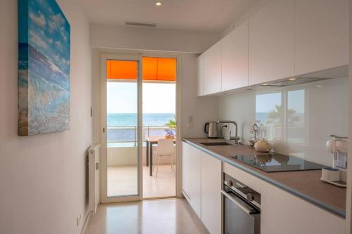 een keuken met witte kasten en uitzicht op de oceaan bij Luxury flat on the Cote d'Azur in Villeneuve-Loubet