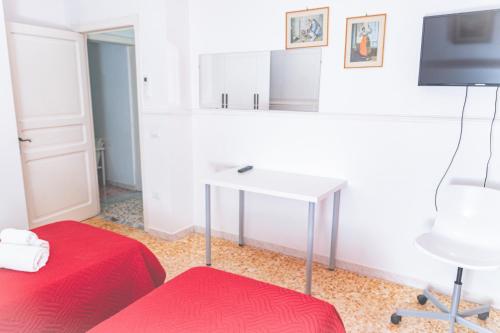 Zimmer mit 2 Betten, einem Schreibtisch und einem TV in der Unterkunft Casa Rosalba in Noto