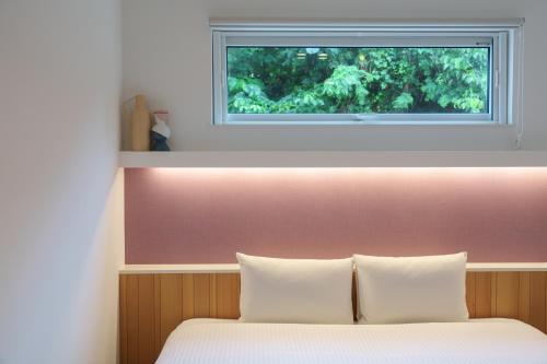 a bed with two pillows and a window above it at クリスタルヴィラ南城 in Azama