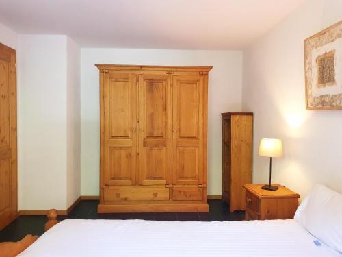 ein Schlafzimmer mit einem Holzschrank und einem Bett in der Unterkunft Alpine Retreat Val D'Illiez in Val dʼIlliez