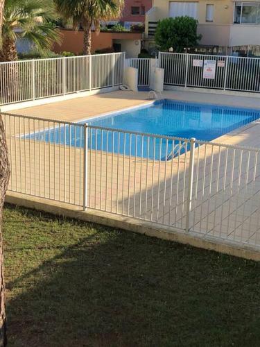 une clôture en face d'une piscine dans l'établissement T1 bis à proximité directe du village naturiste, au Cap d'Agde