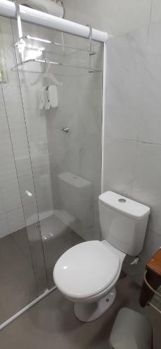 uma casa de banho branca com um WC e um chuveiro em Pousada Container Eco Manguinhos em Manguinhos