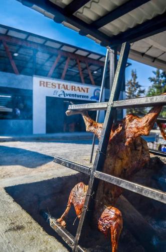 un grill avec de la viande devant un bâtiment dans l'établissement Restaurant El Aventurero, à San Cristóbal