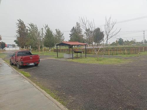 ein roter Truck parkt auf einem Parkplatz neben einem Park in der Unterkunft Restaurant El Aventurero in San Cristóbal