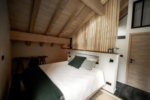 - une chambre avec un lit blanc et un plafond en bois dans l'établissement La Loge de la Dolarde - Chambre Ouest, à Prémanon