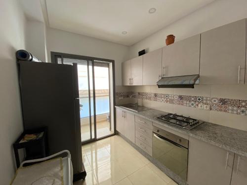 a kitchen with white cabinets and a view of the ocean at Appartement de charme in Kenitra