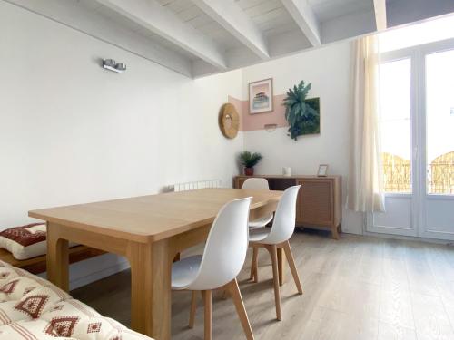 une salle à manger avec une table en bois et des chaises blanches dans l'établissement Large Duplex 2BR in Center of Arcachon 2 min walking beach and Free parking, à Arcachon