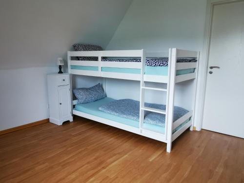 ein weißes Etagenbett in einem Zimmer mit Holzboden in der Unterkunft Charmantes Ferienhaus Casa Ella mit Balkon in Siegen