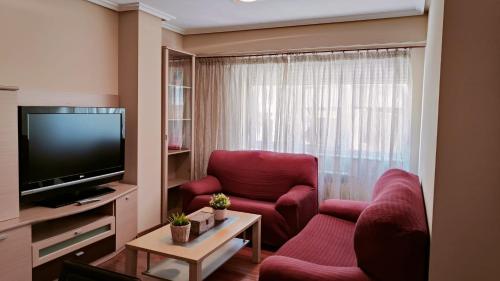 sala de estar con 2 sillas rojas y TV de pantalla plana en Leiras Pulpeiro con Garaje, en Ourense