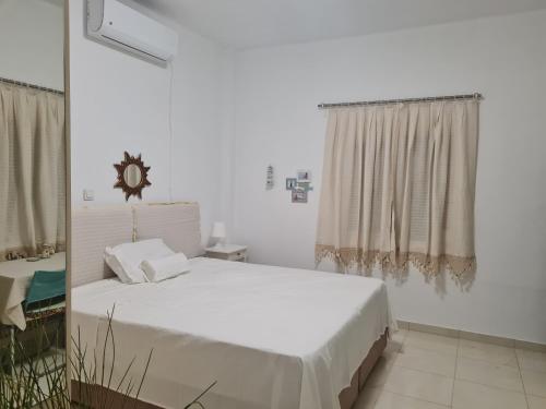 a white bedroom with a bed and a window at Private 24sqm Studio in Lambi, Kos in Kos
