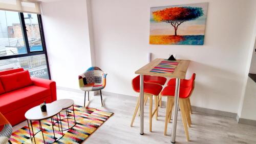 a living room with a red couch and a table and chairs at Toscana LOFT - Apartasuites in Bogotá
