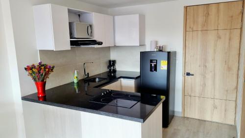 a kitchen with a black refrigerator and white cabinets at Toscana LOFT - Apartasuites in Bogotá