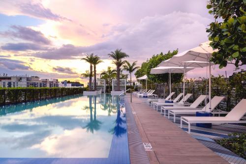 a pool with lounge chairs and umbrellas at a resort at Sentral Wynwood in Miami