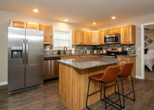 una cocina con nevera de acero inoxidable y armarios de madera en Cedar Hill Heart of Hocking Hills en Rockbridge
