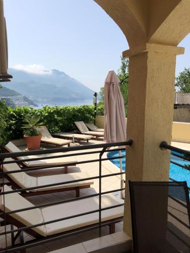 a row of chaise lounge chairs on a balcony with a pool at Apartment "Gluecks-Griff" inside "Becici Sunset Apartments" in Budva
