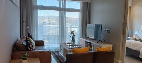 sala de estar con ventana grande y TV en Menlyn Maine Trilogy Apartment 808 en Pretoria