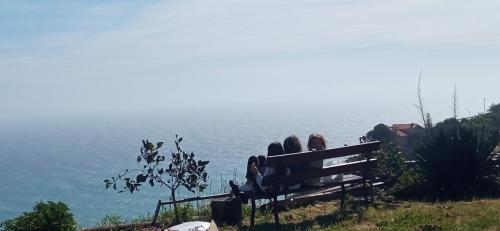 two people sitting on a bench looking at the ocean at Villa CliCla - Pool, sea,hommock swing and laziness in Imperia