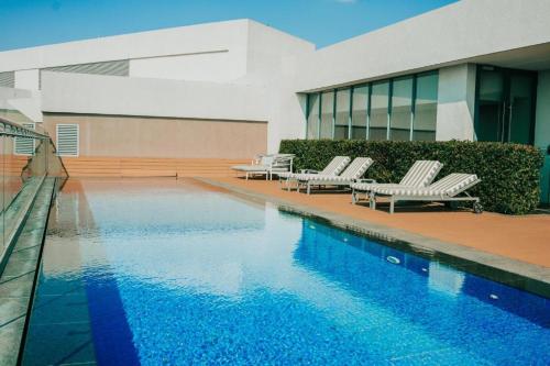 una piscina con 2 tumbonas y un edificio en Menlyn Maine Trilogy Apartment 808, en Pretoria