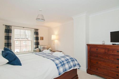 a bedroom with a bed with a dresser and a television at Kissing Gate Cottage in Ebrington