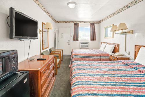 a hotel room with two beds and a flat screen tv at Friendship Inn Hotel in Killeen