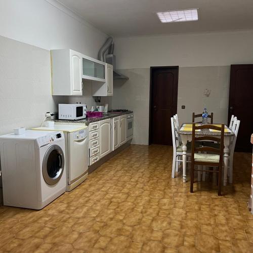 a kitchen with a washing machine and a table with chairs at Alojamento das Laranjeiras in Fernao Ferro