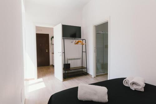 a white room with a black bed and a bathroom at Ballaro' House - rooms with shared kitchen in Palermo