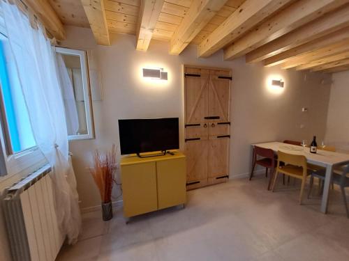 uma sala de estar com televisão num armário amarelo e uma mesa em Ca Jole em Burano