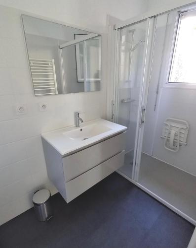 une salle de bain blanche avec un lavabo et une douche dans l'établissement Maison au calme à 10 km du Puy du Fou, aux Herbiers