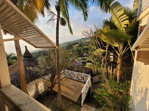 a balcony with a wooden bench and palm trees at Villa Créolia in Saint-Leu