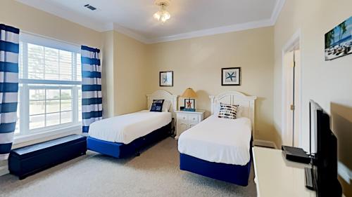 a bedroom with two beds and a tv and a window at Pawleys Island Retreat Tranquil 4BR Pool Tennis in Pawleys Island
