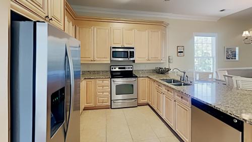 a kitchen with wooden cabinets and a stainless steel refrigerator at Pawleys Island Retreat Tranquil 4BR Pool Tennis in Pawleys Island